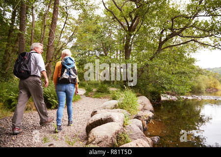 Rear View Of Senior Couple Hiking Along Path By Lake In UK Lake District Stock Photo