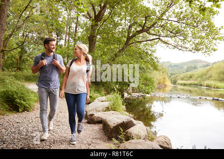 Couple Hiking Along Path By River In UK Lake District Stock Photo