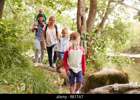 Family Hiking Along Path By River In UK Lake District Stock Photo