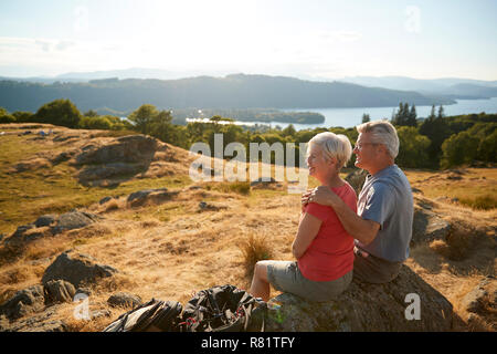 Senior Couple Resting At Top Of Hill On Hike Through Countryside In Lake District UK Stock Photo
