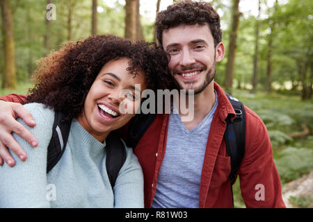 A young adult mixed race couple laughing to camera during a hike in a forest, portrait Stock Photo