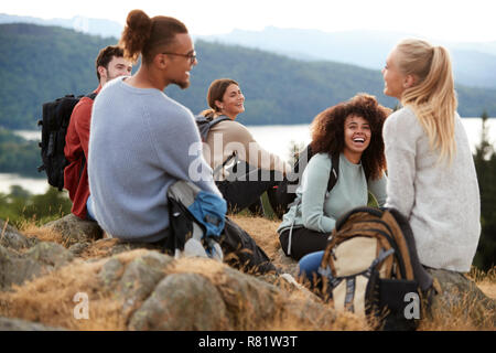 Five young adult friends sit talking at the summit after a mountain hike, close up