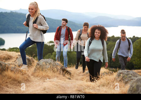 A group of five young adult friends smiling while hiking to a mountain summit Stock Photo