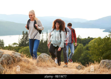 A group of mixed race young adult friends smiling while hiking to a mountain summit Stock Photo