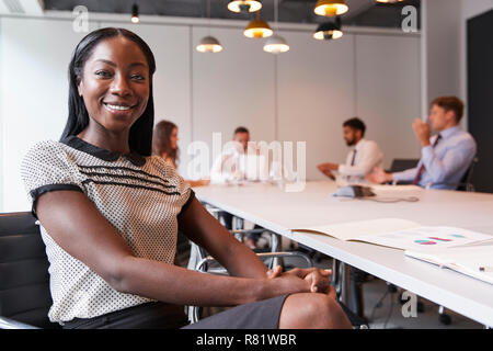 Portrait Of Businesswoman In Modern Boardroom With Colleagues Meeting Around Table In Background Stock Photo