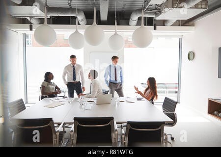Businessmen And Businesswomen Meeting Around Table In Modern Boardroom Stock Photo