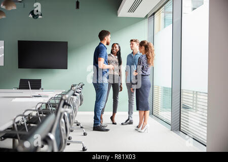 Casually Dressed Businessmen And Businesswomen Having Informal Meeting In Modern Boardroom Stock Photo
