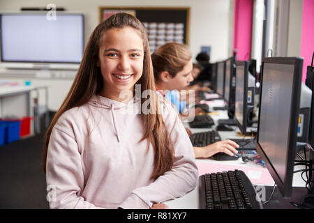 Portrait Of Smiling Female Pupil Sitting In Line Of High School Students Working at Screens In Computer Class Stock Photo