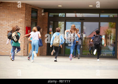 Group Of High School Students Running Into School Building At Beginning Of Class Stock Photo