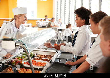 High School Students Wearing Uniform Being Served Food In Canteen Stock Photo