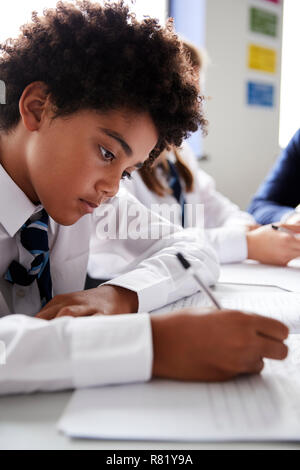 Male High School Student Wearing Uniform Working At Desk Stock Photo