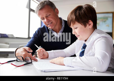 High School Tutor Giving Male Student Wearing Uniform One To One Tuition At Desk Stock Photo