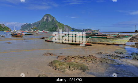 Tour and fishing boats stranded and moored at the beach of Bacuit bay at low tide in a sunny morning ready for going out to sea on their usual fishing Stock Photo