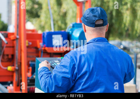 Worker pressing buttons on CNC machine control board in factory. Stock Photo