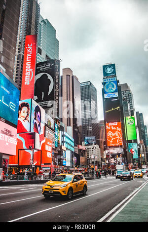 New York City, USA - Nov 28 2018: Typical street scene in Times Square, NYC, with yellow cab taxi and bright lights of adverts on high-rise buildings Stock Photo