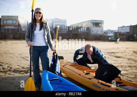 Portrait of a smiling mid-adult couple with kayaks on a sandy beach. Stock Photo