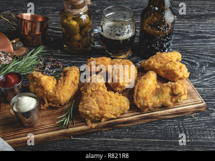 fried chicken wings in batter, red and white sauce on a dark surface Stock Photo