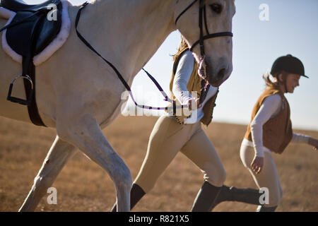 Woman and girl running with horse in a field Stock Photo