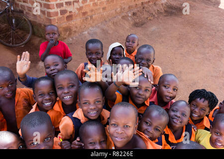 A group of happy primary-school children smiling, laughing and waving. They are dressed in school uniforms. Stock Photo