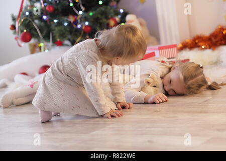 Merry Christmas and Happy Holidays Cute little child girl is decorating the Christmas tree indoors. Stock Photo