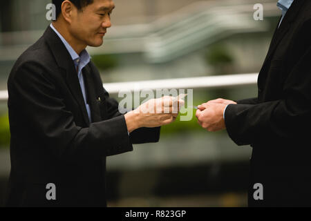 Two mid-adult businessmen exchanging business cards in the city. Stock Photo