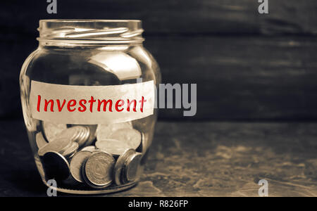 Glass jar with coins and the inscription ' Investment '. Investing in a new business project or real estate. Concept of economic financing. Saving mon Stock Photo