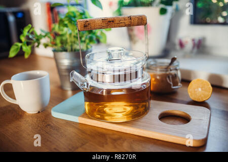 Composition of tea in a teapot, sugar, lemon and cup on wooden table. Stock Photo