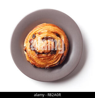 Freshly baked sweet bun with raisins on grey plate isolated on white background, top view Stock Photo