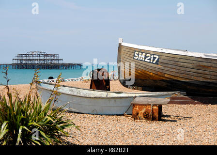 Old fishing boat, SM217, on beach at Brighton, East Sussex, England, with remains of West Pier beyond Stock Photo