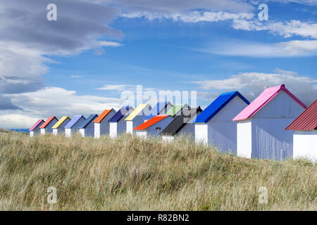 Row of colourful beach cabins in the dunes at Gouville-sur-Mer, Lower Normandy, France Stock Photo