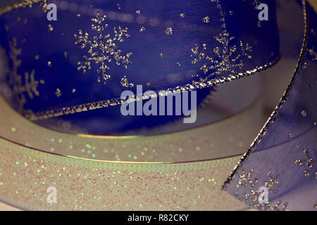 Glittery blue and white sheer fabric Christmas holiday ribbon abstract background with snowflakes Stock Photo