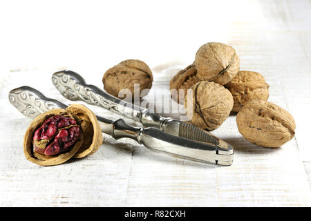 Red Danube Walnuts with silver nutcracker on wooden background Stock Photo