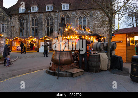 Winchester, Hampshire, England, December 12 2018. Christmas market stalls in the grounds of Winchester Cathedral with one selling gluhwein Stock Photo