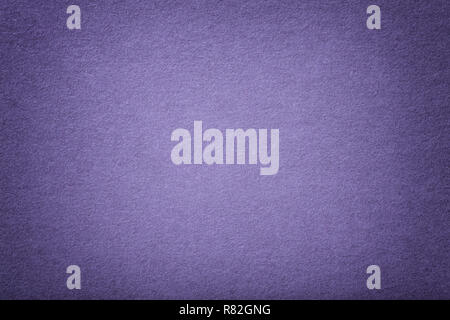 Dark violet matte background of suede fabric, closeup. Velvet texture of seamless lavender woolen felt with vignette. Stock Photo