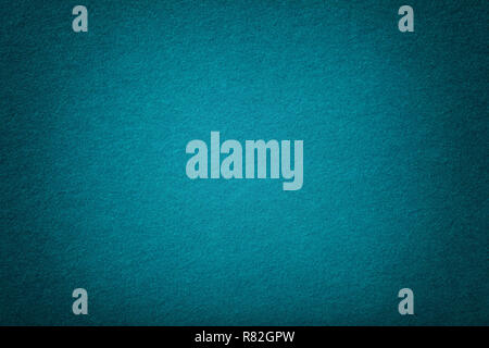 Dark turquoise matte background of suede fabric, closeup. Velvet texture of seamless navy blue woolen felt with vignette. Stock Photo