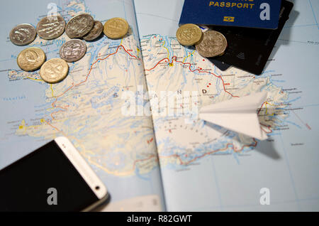 Coins of Iceland, the plane, smartphone, biometric passport, dollars, coins and credit cards lie on a map of Iceland Stock Photo