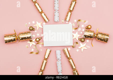 Gold Christmas cracker with a blank white label. luxury gold festive cracker on a pastel pink background Stock Photo