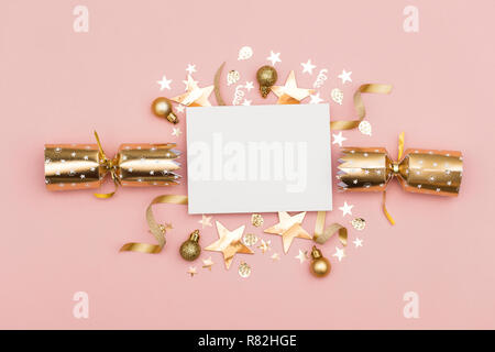 Gold Christmas cracker with a blank white label. luxury gold festive cracker on a pastel pink background Stock Photo