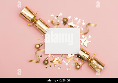 Gold Christmas cracker with a blank white label. luxury gold festive cracker on a pastel pink background Stock Photo