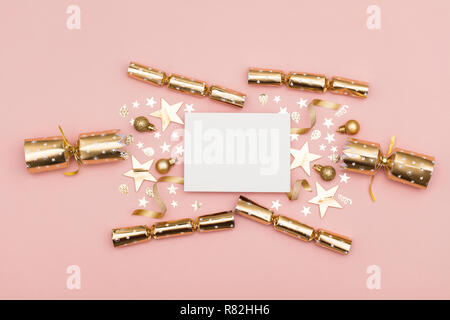 Gold Christmas cracker with a blank white label. luxury gold festive cracker on a pastel pink background Stock Photo