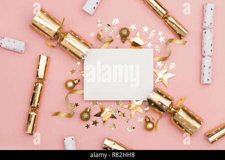 Gold Christmas cracker with a blank white label. luxury gold festive cracker on a pastel pink background Stock Photo