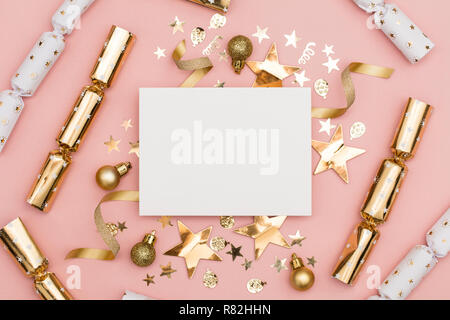 Gold Christmas cracker with a blank white label. luxury gold festive cracker on a pastel pink background Stock Photo