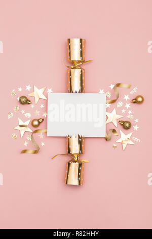 Gold Christmas cracker with a blank white label. luxury gold festive cracker on a pastel pink background Stock Photo