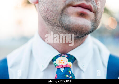 Close up of mouth and shoulders of stylish man wearing blue tie and suspenders
