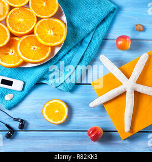 Oranges, towel, headphones and starfish on blue wooden background. Summer holiday concept Stock Photo