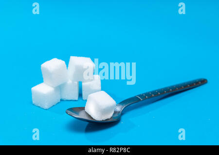 Background of sugar cubes in spoon. White sugar on blue background. Sugar with copy space Stock Photo