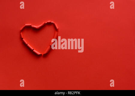Ripped paper hole heart shaped on red paper background. Valentine's day celebration concept Stock Photo