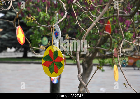 Several wooden Easter eggs painted by hands and hanging on the branches. Stock Photo