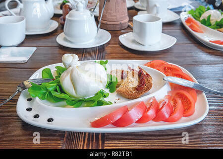 Burato cheese and lettuce for the correction of the weight of the leaves of Lollo Rosso lettuce and tomatoes. Restaurant food. The concept of healthy  Stock Photo