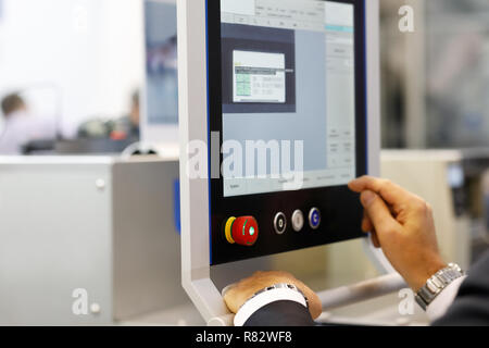 Engineer using industrial touchscreen computer at an automated production line. Selective focus. Stock Photo
